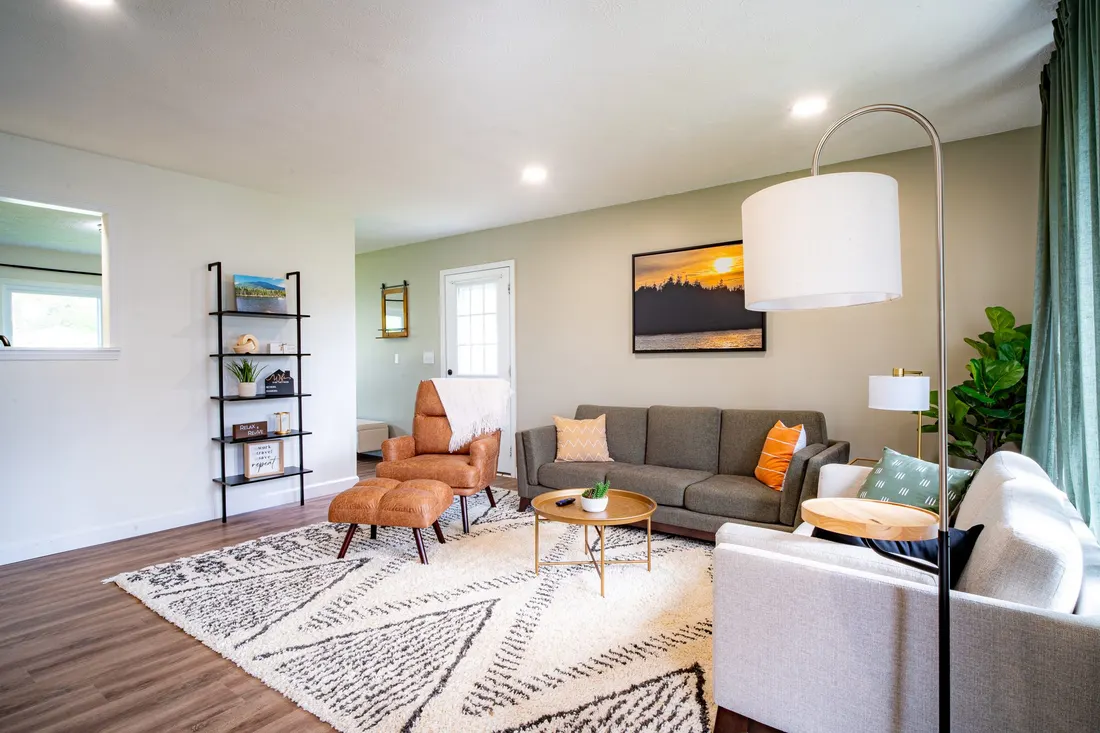 Modern living room with a grey sofa, leather accent chair, and area rug.