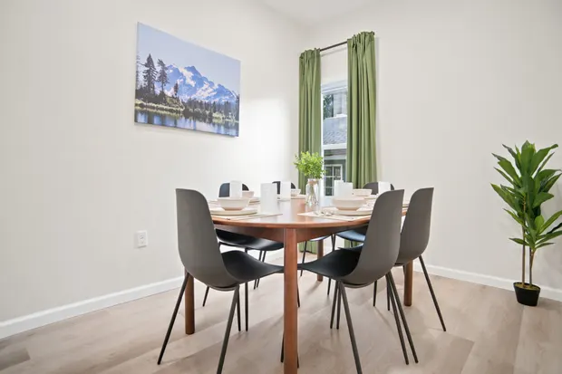 Dining table with four chairs and framed mountain artwork on the wall.
