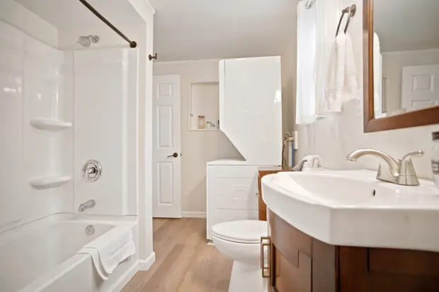 Bathroom with a tub/shower, wood vanity, and a mirror.