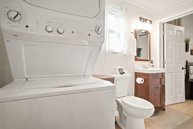 Bathroom with a stacked white washer and dryer, toilet, and a wood vanity.