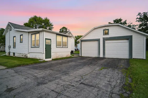 The house and detached garage at dusk under a pink and blue sky.
