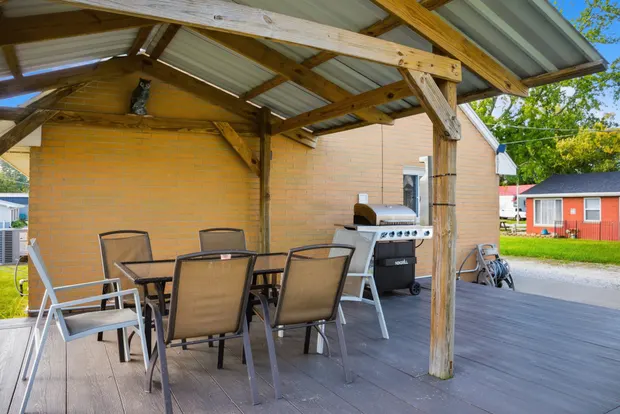 Covered deck with a dining table for six and a gas grill.