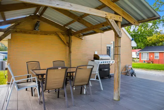 Covered deck with a dining table for six and a gas grill.
