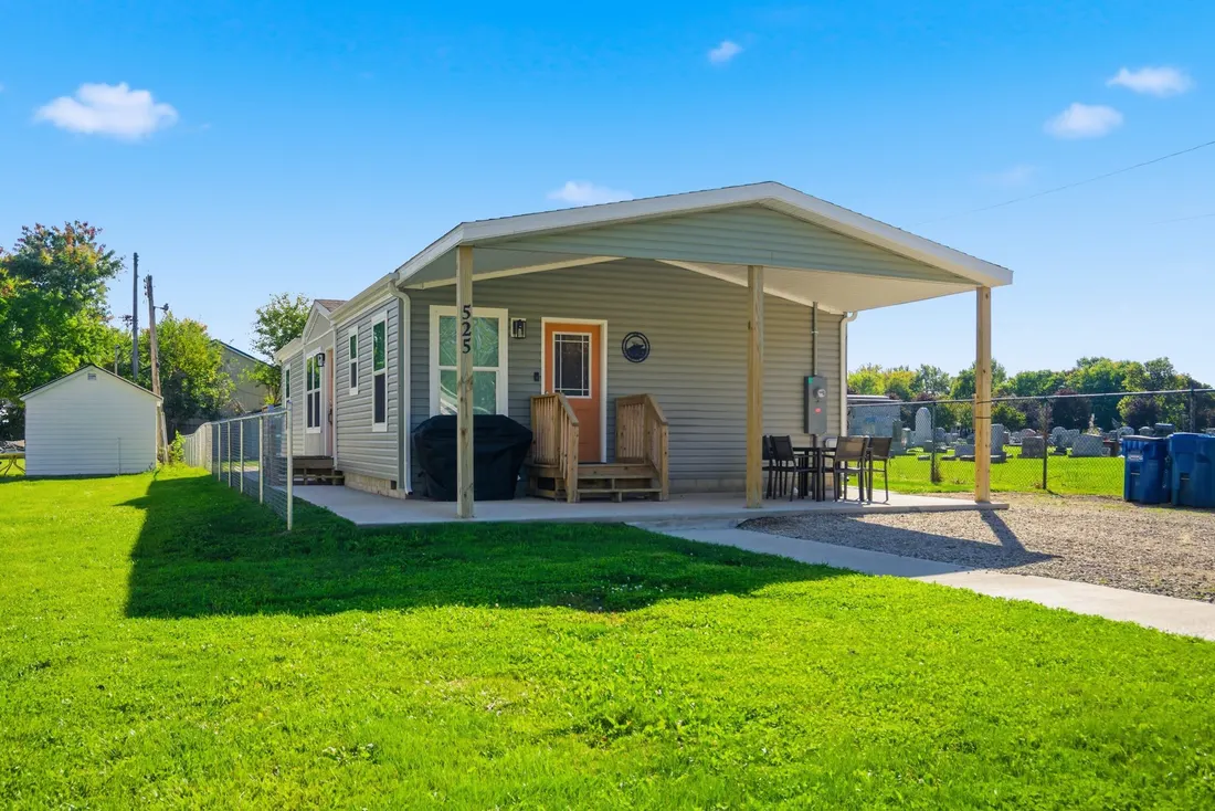 Exterior of the single-level grey ranch home with a covered front porch and a green lawn.