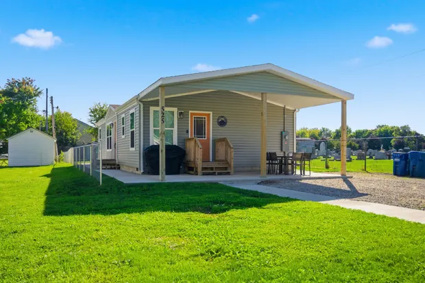 Exterior of the single-level grey ranch home with a covered front porch and a green lawn.