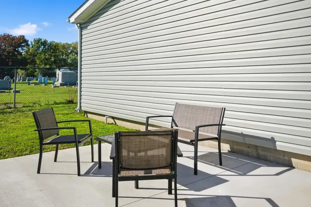 Side of the home with grey siding and a paved walkway.