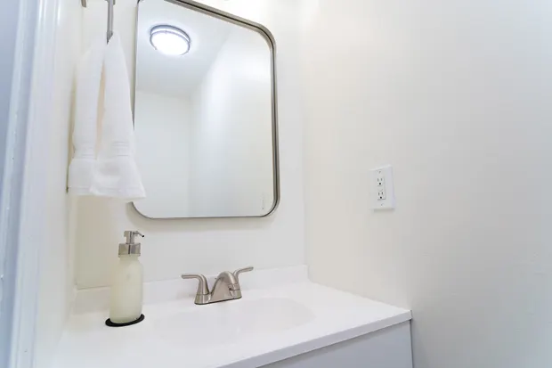 Private half bath with a vanity sink and mirror.