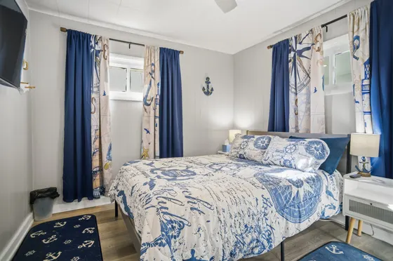 Main-floor bedroom with a queen bed, nautical blue bedding, and anchor decor.