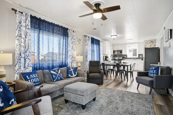 Living room with a sectional sofa, ceiling fan, "Lake House" pillows, and a dining area beyond.