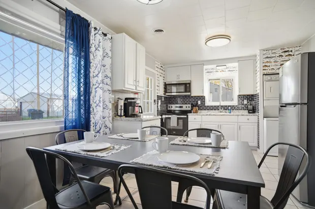 Dining table with place settings, open to the kitchen.