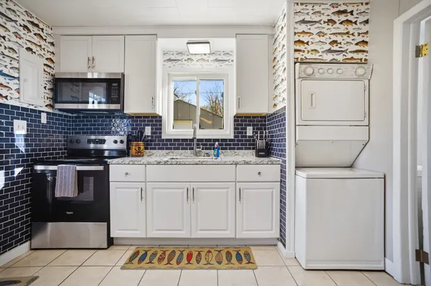 Kitchen with white cabinets, granite counters, and a stacked washer and dryer.