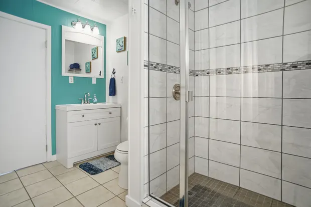 Main-floor bathroom with a teal accent wall and a glass walk-in shower.