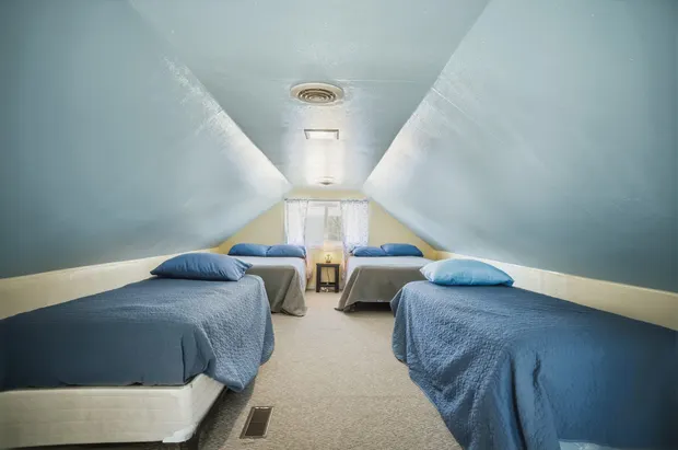Upstairs sleeping loft with beds under a sloped blue-painted ceiling.