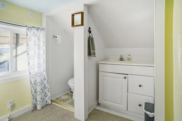 Loft half bath with a vanity and toilet under a sloped ceiling.