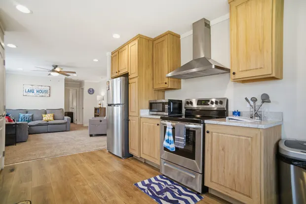 Kitchen with light cabinets, stainless refrigerator, and range, open to the living room.
