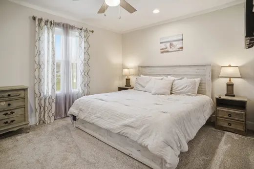 Primary bedroom with a king bed, upholstered headboard, and a ceiling fan.