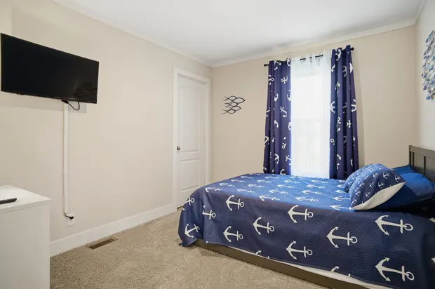 Third bedroom with nautical anchor bedding and a wall-mounted TV.