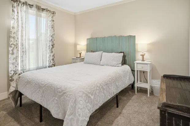 Second bedroom with a queen bed and a soft green headboard.