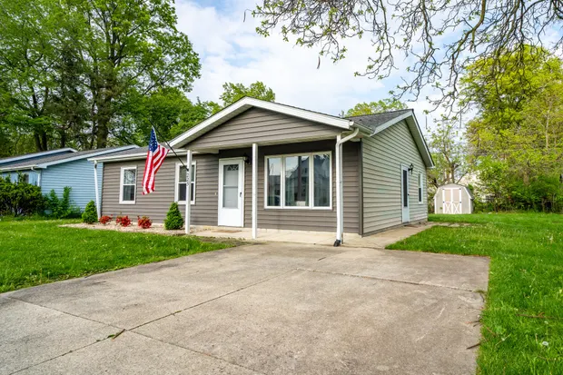 Grey house and driveway with an American flag out front.