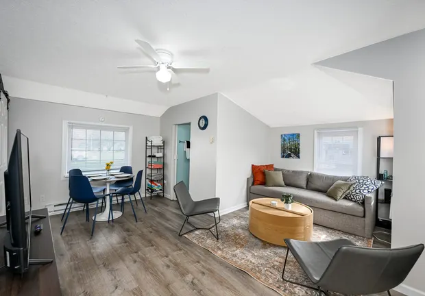 Open living and dining area with a grey sofa, small dining set, and wood-look floors.