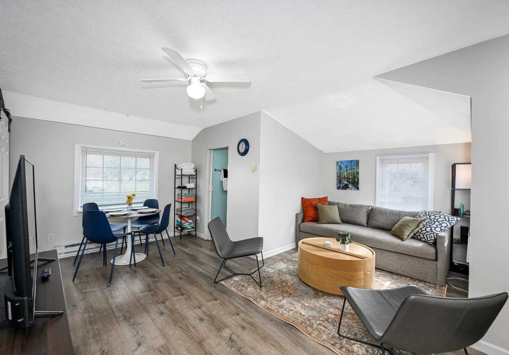 Open living and dining area with a grey sofa, small dining set, and wood-look floors.