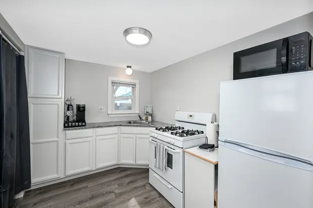 Kitchen with white cabinets, a gas range, and a full-size refrigerator.