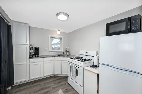 Kitchen with white cabinets, a gas range, and a full-size refrigerator.