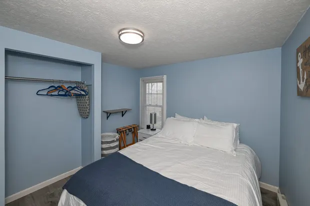 Blue bedroom with a queen bed and an open closet.