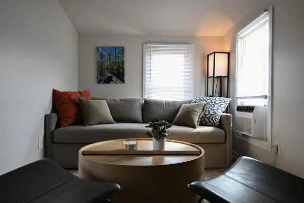 Grey sofa with colourful pillows beside a window.