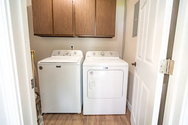 White washer and dryer under wood cabinets.