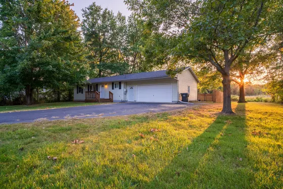 Single-storey home on a wide green lawn with mature trees at golden hour.