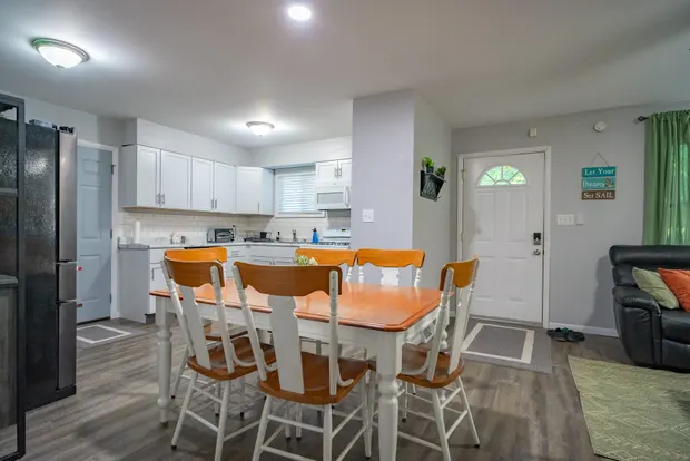 Wooden dining table with six chairs beside the kitchen.