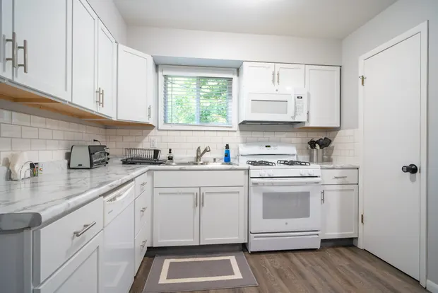 Kitchen with white cabinets, a gas range, and a subway-tile backsplash.