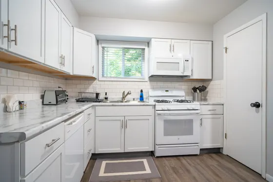 Kitchen with white cabinets, a gas range, and a subway-tile backsplash.