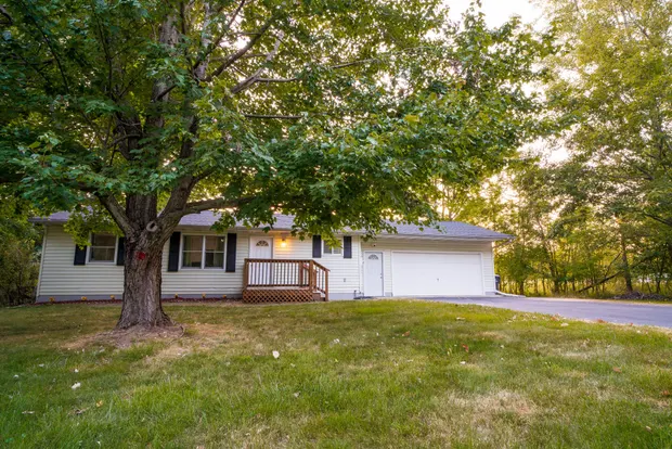 Front of the home with its entry deck and a large shade tree.