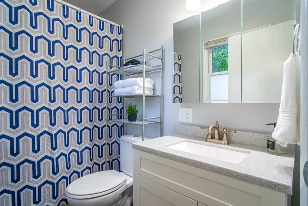 Bathroom with a tub/shower combo and a blue patterned shower curtain.