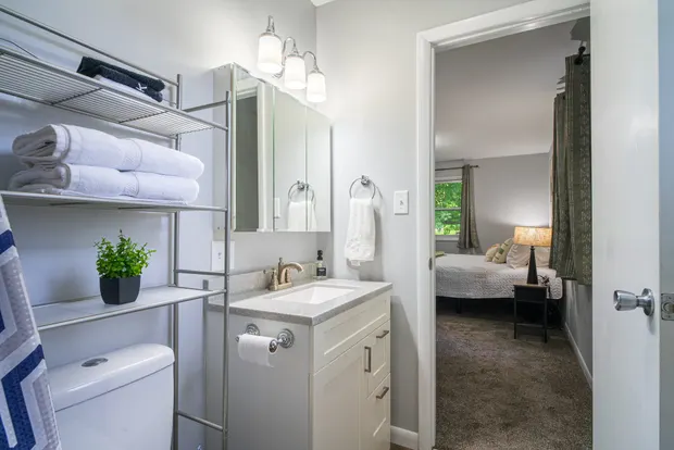 Bathroom vanity with a mirror and open shelving stacked with towels.