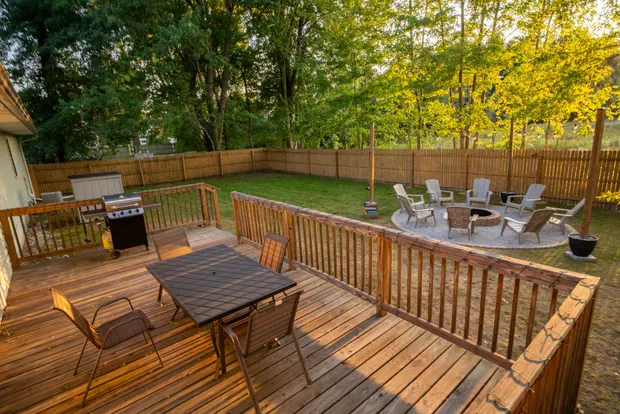 Back deck with an outdoor dining table and seating overlooking the fenced yard.