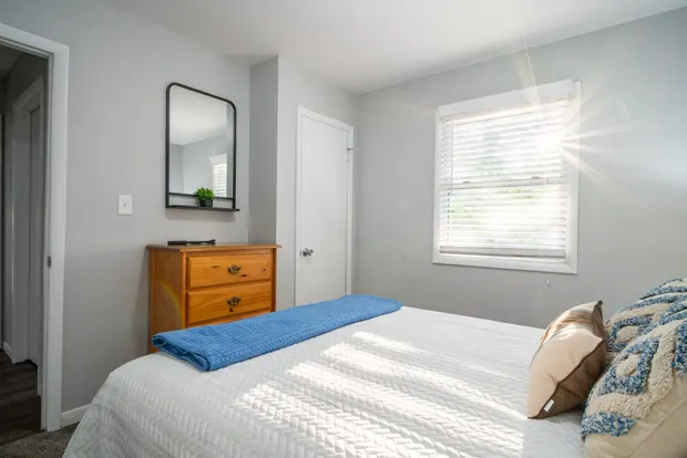 The third bedroom from another angle, with a mirror and window.