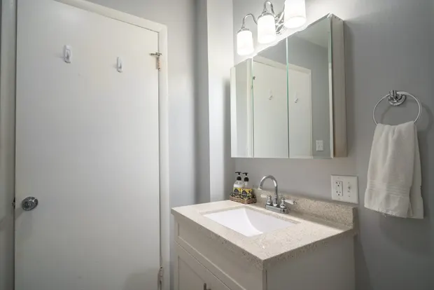 Second full bathroom with a vanity, mirror, and tub/shower combo.