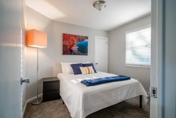 Queen bedroom with an orange lamp and framed art above the bed.