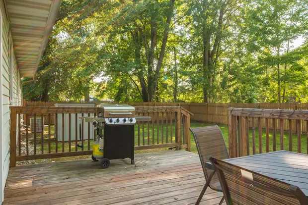 Gas grill on the back deck beside the fenced backyard.
