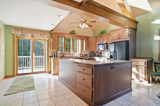 Spacious kitchen with wooden island, vaulted beamed ceiling, and sliding glass doors.