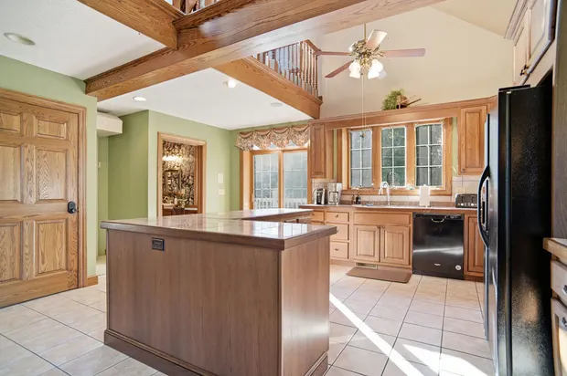 Traditional oak kitchen with center island and vaulted ceiling with exposed wood beams.