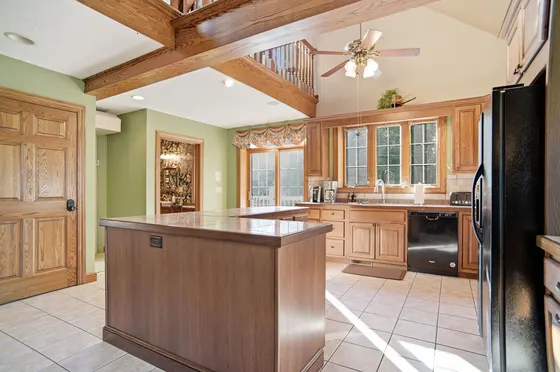 Traditional oak kitchen with center island and vaulted ceiling with exposed wood beams.