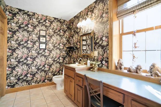 Bathroom with bold floral monkey wallpaper and wooden vanity desk.