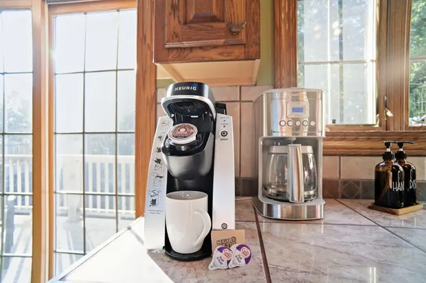 Kitchen coffee station with Keurig and drip coffee makers on a tiled counter.