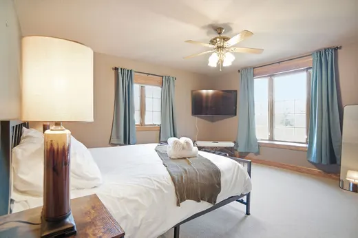 Cozy bedroom with a large bed, wall-mounted TV, and blue window curtains.