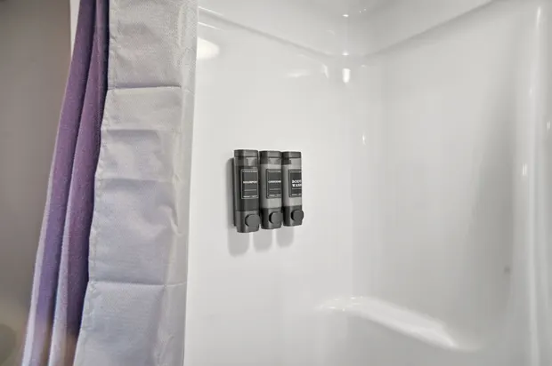 Bathroom shower stall with wall-mounted shampoo and body wash dispensers.