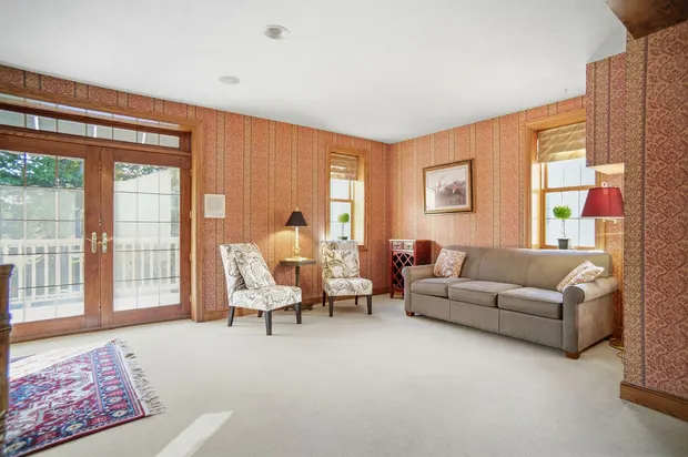 Bright sitting room with patterned wallpaper, sofa, and french doors.